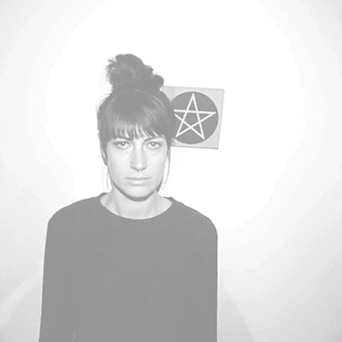 a person stands in front of a small pentagram hanging on the wall