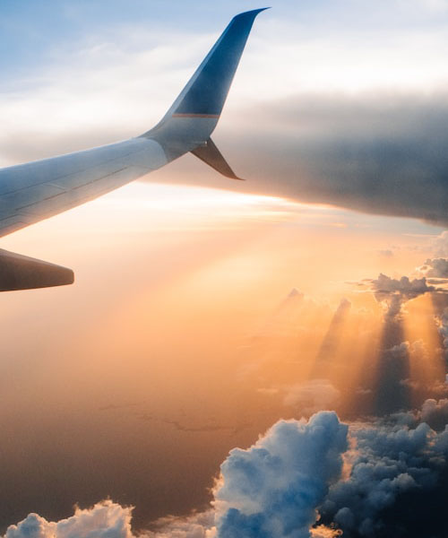 Airplane wing above clouds at sunset