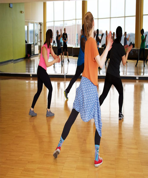 A picture of a group of people practicing a dance routine at a dance studio with mirrors.