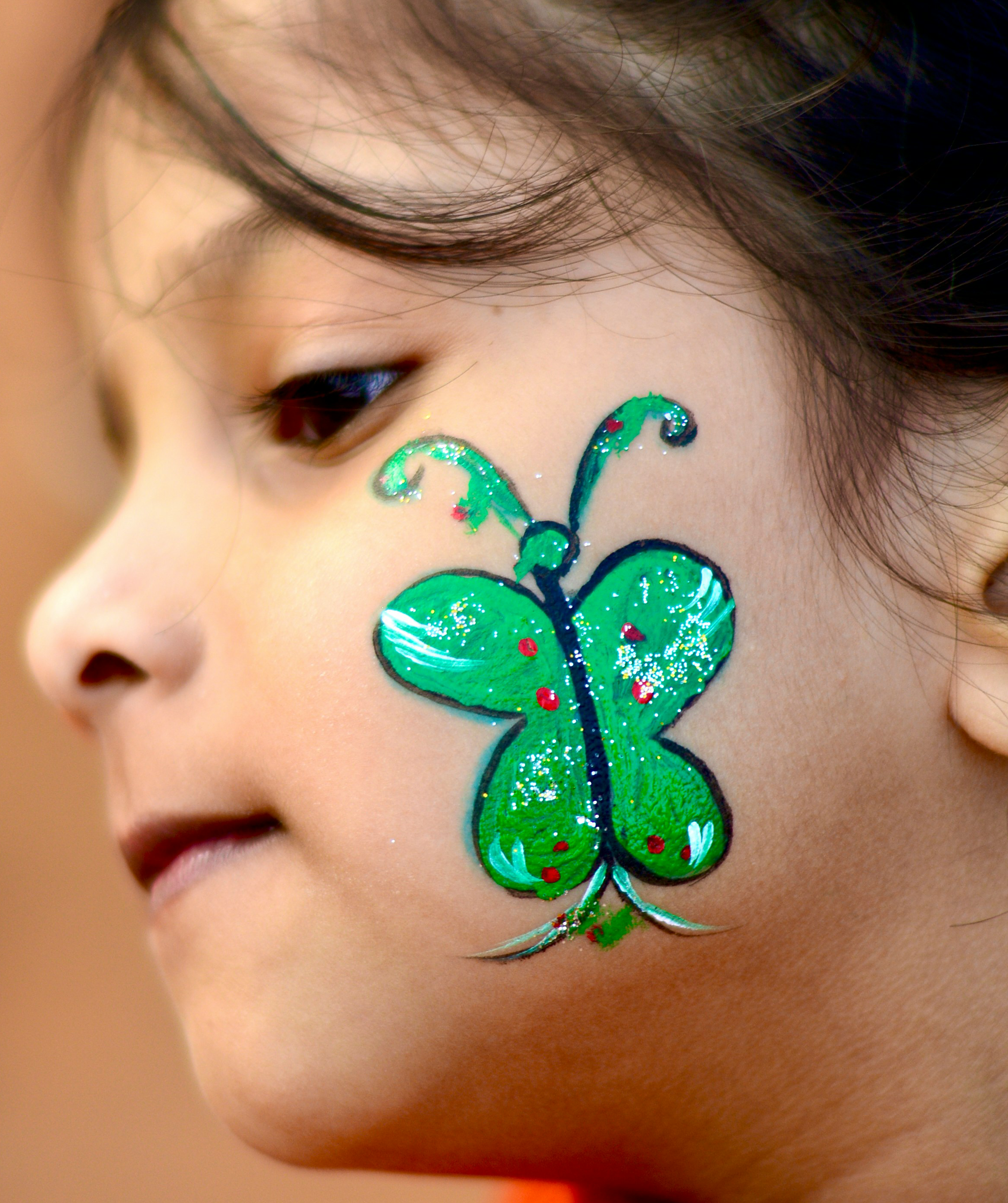 Young girl with green butterfly face paint