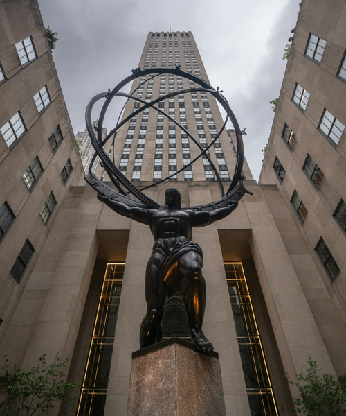 Atlas statue holding a globe in front of a tall building