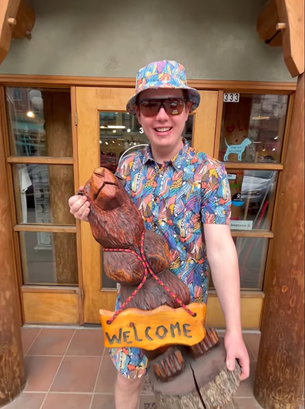 A well dressed gentleman holding a wooden bear