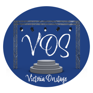 A dark blue circle, inside the circle is a circular stage with metal scafolding that has spotlights hanging from it. On the stage is the letters VOS in cursive font. Underneath the circular stage there a cursive font that says Victoria Onstage"