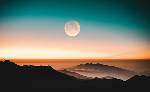 full moon above the desert at sunset